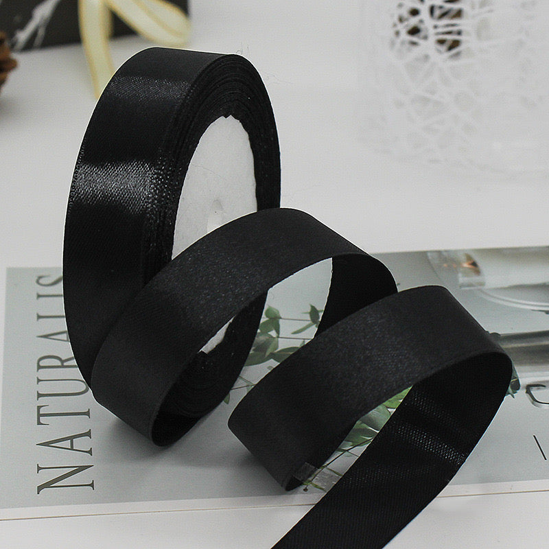 🧵 Premium Satin Ribbon – Versatile & Elegant, black satin ribbon roll on a table for gift wrapping and craft projects.