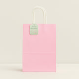 Pink paper bag with a white handle on a light beige background