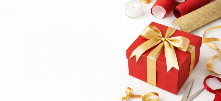 Red gift box with a gold ribbon and scissors on a white background